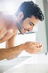 Close up of man washing face at sink