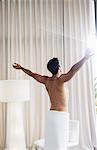 Man in towel basking in sunlight at window