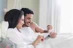 Couple using digital tablet in bed