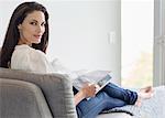 Portrait of confident woman reading magazine on chaise lounge