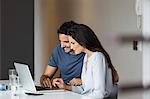 Couple using laptop at table