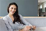 Portrait of smiling woman knitting on sofa