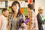 Portrait of confident casual businesswoman with co-workers passing in background