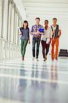 Portrait of creative business people walking in sunny corridor