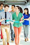 Creative business people with folders walking in office corridor