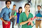 Portrait of creative businesswoman with folder and co-workers in corridor