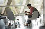 Businessman reviewing paperwork at circle of chairs