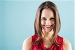 Close-up portrait of teenage girl looking at camera and smiling, studio shot on blue background