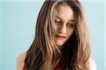 Close-up portrait of teenage girl looking downwards, studio shot on blue background