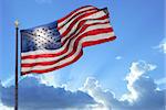 American flag waving in the wind back lit by sun