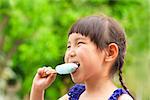 happy little girl eating popsicle at summertime