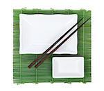 Chopsticks and utensils over bamboo mat. Isolated on white background