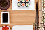 Japanese food and fresh sakura branch over bamboo table with copy space