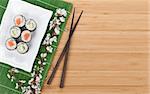 Sushi set with fresh sakura branch over bamboo table with copy space