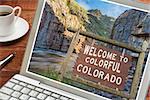Colorado welcome sign on a laptop with a cup of coffee - planning vacations concept