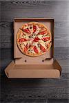 Italian pizza with ham and tomatoes in box, on gray table background