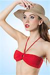 summer girl in red bikini with a hat . looking up and keeping the hat with one hand