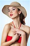 Young girl is holding her hend near body , wearing a red bra and summer hat . very expressive face