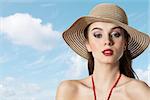 pretty portrait of beautiful young woman with summer hat looking in camera on blue sky
