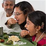 Indian family dining at home. Candid photo of Asian people eating rice with hands. India culture.