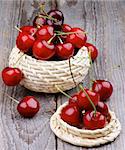 Ripe Sweet Cherries in Wicker Bowls isolated on Rustic Wooden background