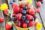 Fresh cherry, strawberry, blueberry and raspberry in a bucket on wooden table