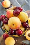 Fresh apricot and cherry in a yellow bucket