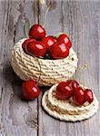 Red Sweet Cherries in Wicker Bowl isolated on Rustic Wooden background