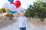 running cheerful boy holding colorful balloons and celebrating 4th of July