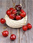 Red Ripe Sweet Cherries in Wicker Bowl isolated on Rustic Wooden background