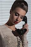 elegant female with vintage make-up talking on the retro phone with receiver