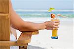 Pretty blonde sitting in deck chair with a cocktail on a sunny day