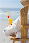 Woman relaxing in deck chair by the sea holding cocktail on a sunny day