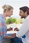 Happy young couple sitting in the garden enjoying wine together on a sunny day