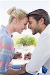 Happy young couple sitting in the garden enjoying wine together on a sunny day