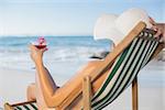 Woman relaxing in deck chair with cocktail on a sunny day