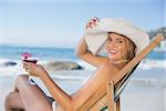 Smiling woman relaxing in deck chair with cocktail on a sunny day