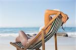 Woman relaxing in deck chair on the beach on a sunny day