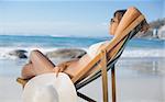 Pretty woman relaxing in deck chair on the beach on a sunny day