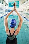 Fit swimmer in the pool with arms raised at the leisure center