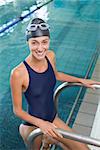 Fit swimmer smiling at camera getting out of the swimming pool at the leisure center