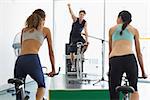 Fit women doing a spin class with enthusiatic instructor at the gym