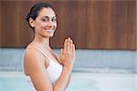 Content brunette in white sitting in lotus pose in health spa
