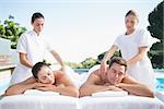 Calm couple enjoying couples massage poolside outside at the spa