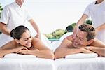 Smiling couple enjoying couples massage poolside outside at the spa