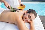 Smiling woman getting an aromatherapy treatment poolside outside at the spa