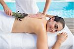 Smiling brunette getting an aromatherapy treatment poolside outside at the spa