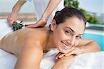 Smiling brunette getting an aromatherapy treatment poolside outside at the spa