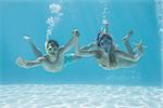 Cute couple underwater in the swimming pool with snorkel and starfish on their holidays