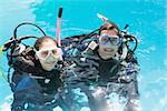 Smiling couple on scuba training in swimming pool looking at camera on a sunny day